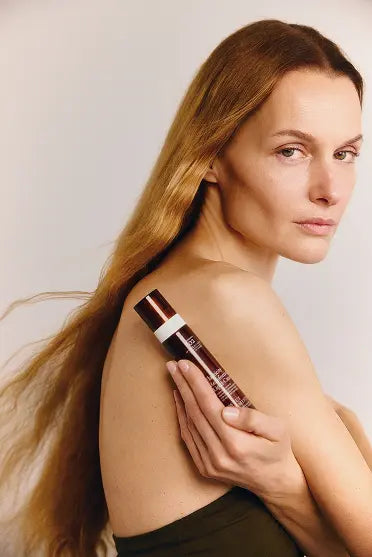 Woman holding a Sweet Chemistry bottle with a plain background